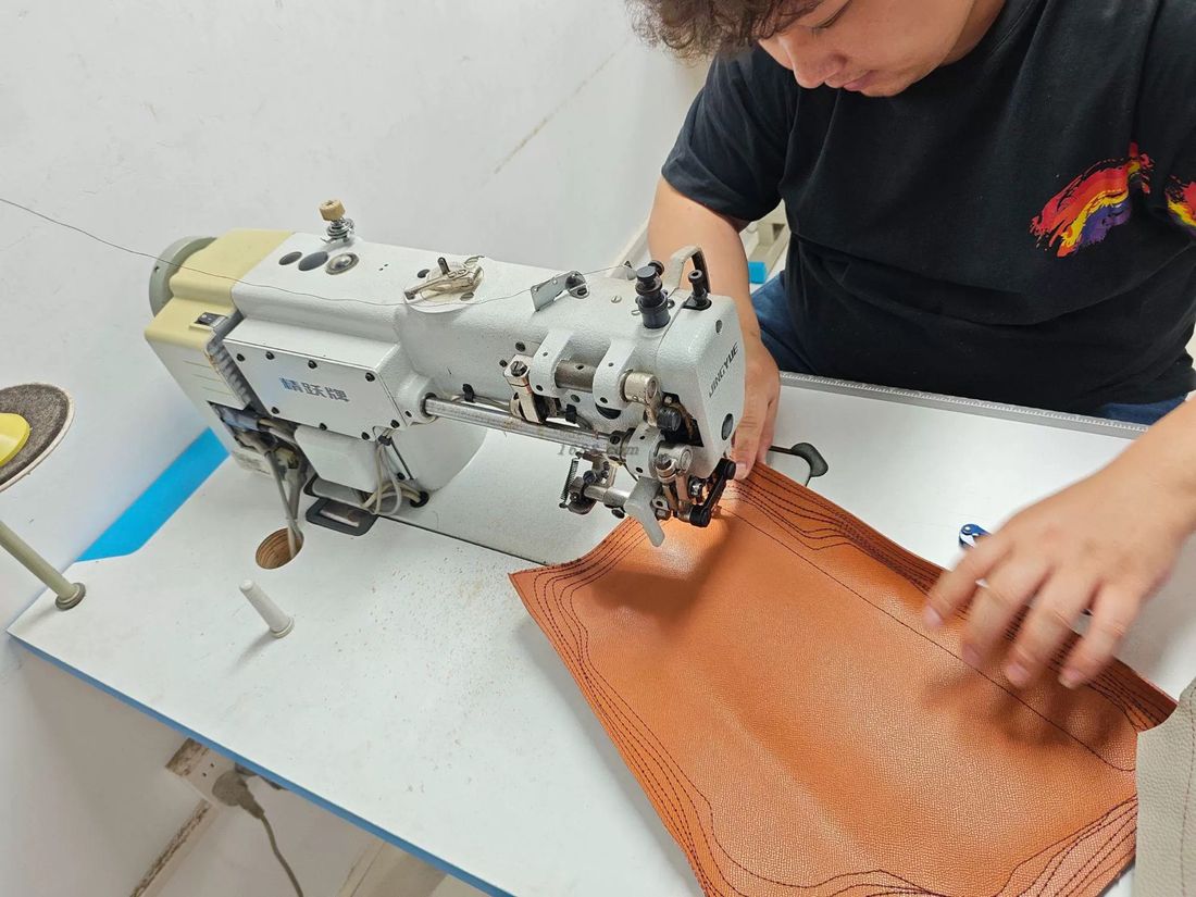 Craftsman sewing leather bags on production line